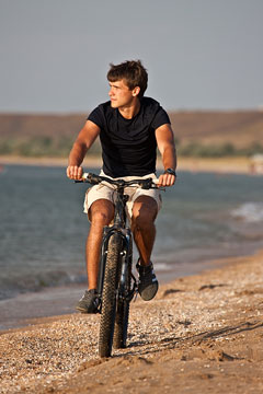 bicycle rider, riding along a beach