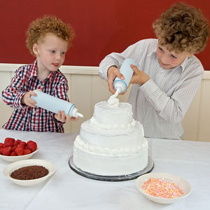 two children decorating a cake