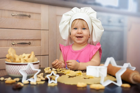 little girl chef baking cookies in a kitchen